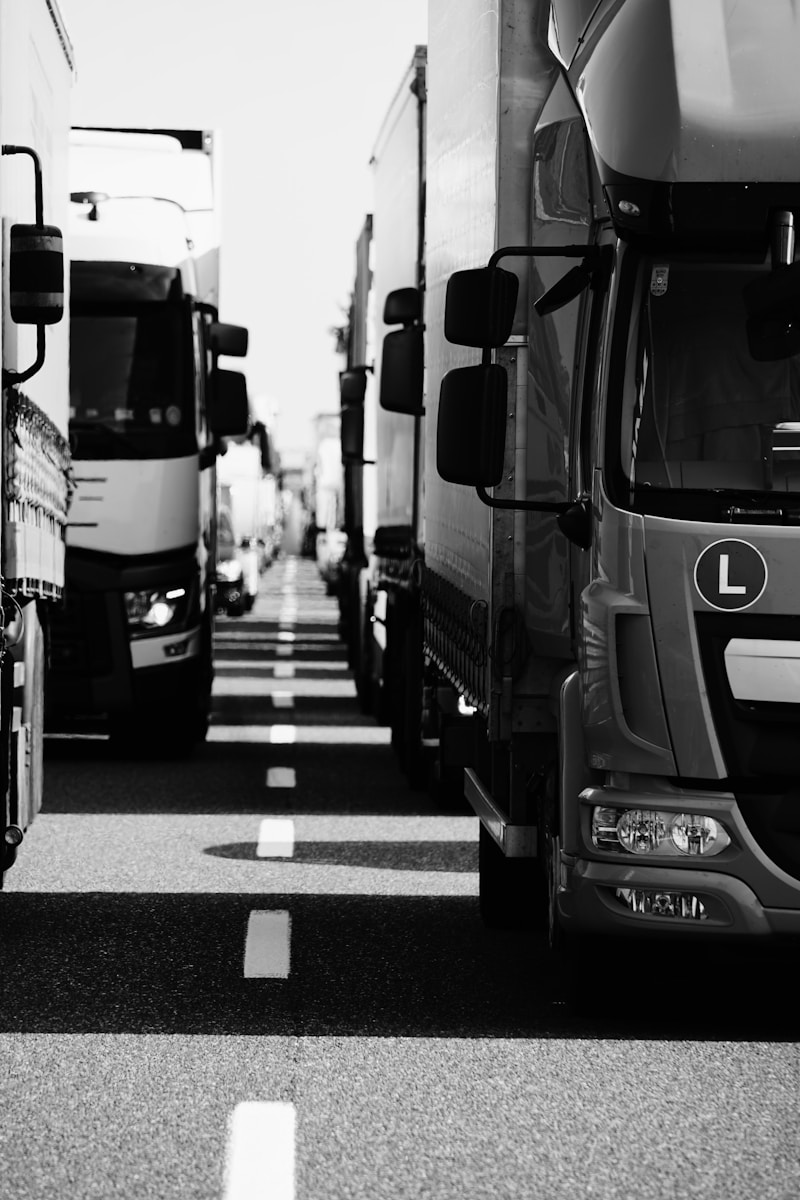 grayscale photo of trucks with liability coverage on the road